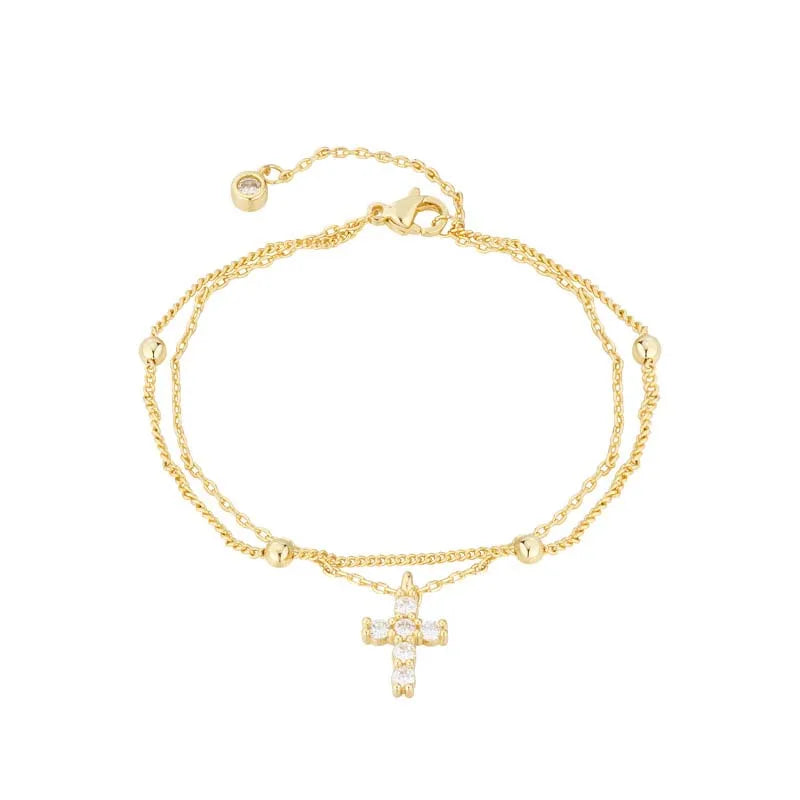 Gold bracelet with a cross pendant on a white background