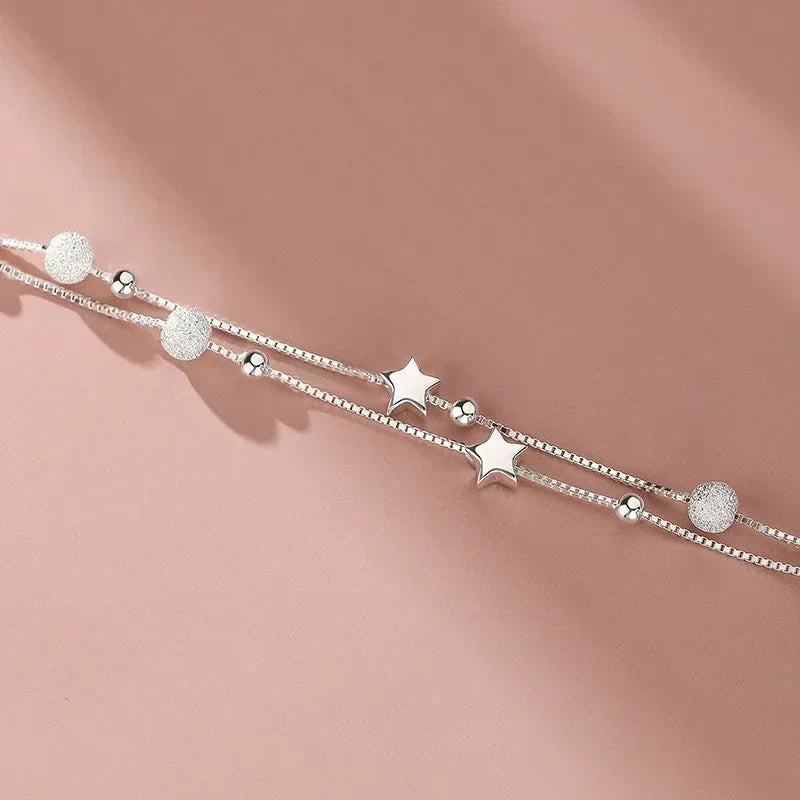 Detail shot of the Serena Delicate Silver Bracelet's layered chain, beads and star charms